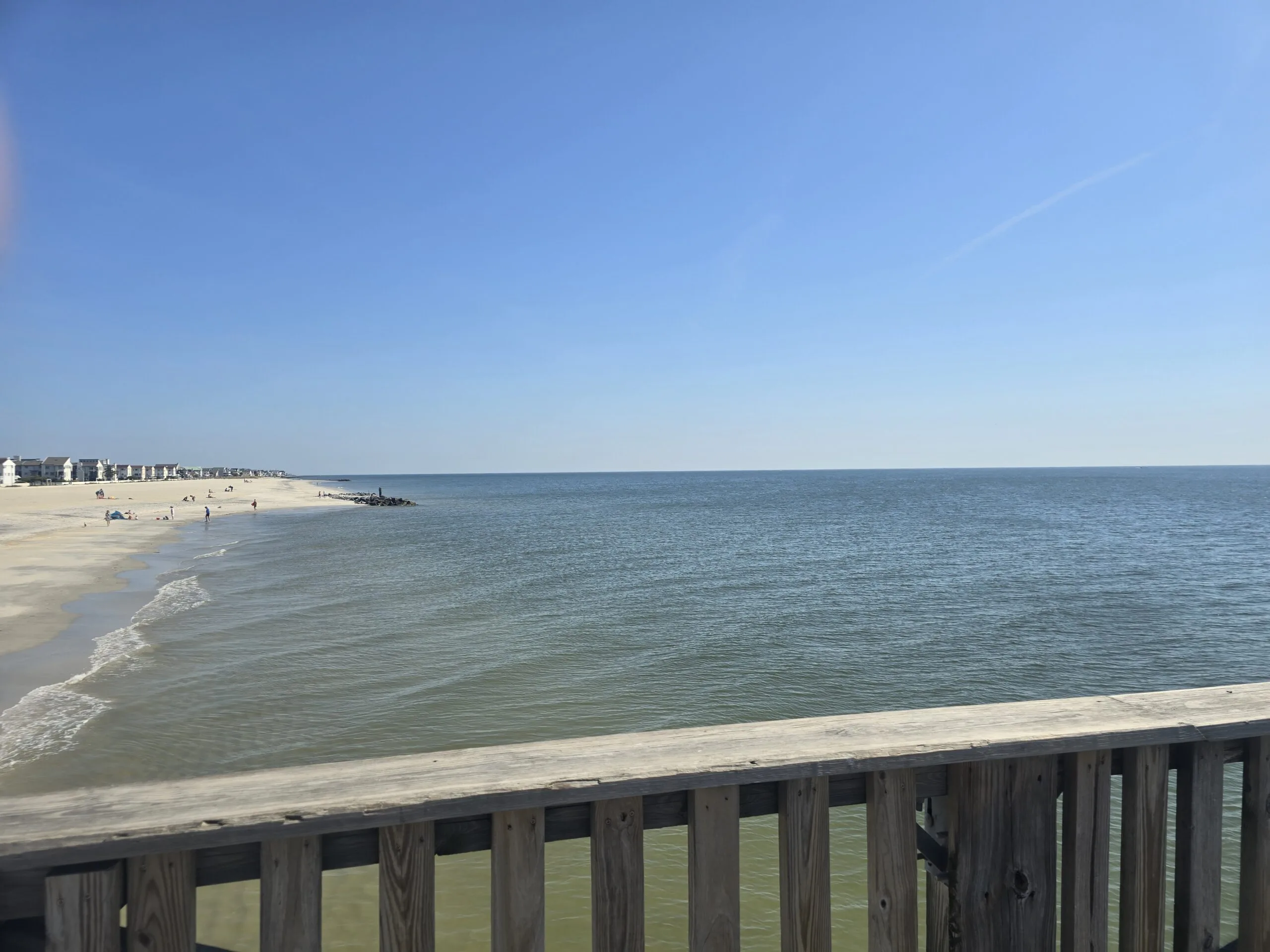View of the ocean and sandy shoreline from the Buckroe Beach pier in Hampton, VA