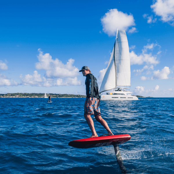 Rider on red eFoil with sailboat in background