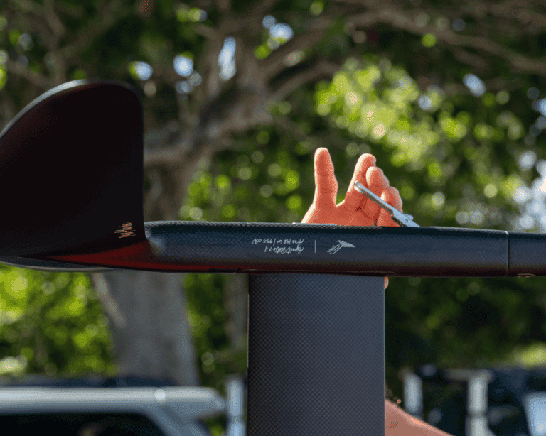 Close-up of Lift eFoil wing mast with safety tether looped by rider’s hand