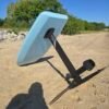 Side view of a custom light blue electric hydrofoil eFoil board with black foil mast and wings on the sand at Buckroe Beach in Hampton, Virginia.