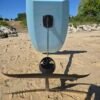 Rear view of a light blue electric hydrofoil eFoil board with foil wings and propulsion system on the sand at Buckroe Beach in Hampton, Virginia.